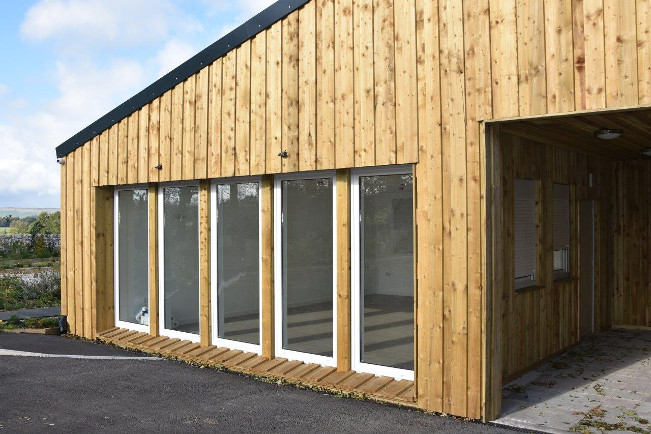 A timber-clad modular building with full-height glazing