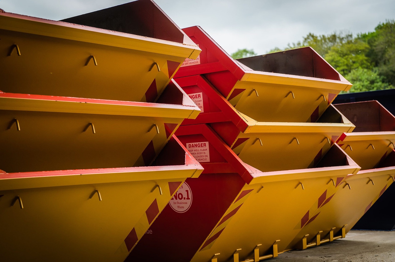 Stacked yellow and red skips in a yard