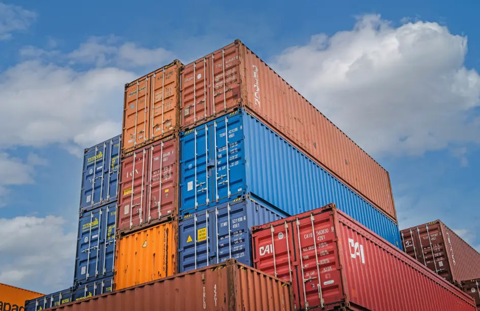Stacked shipping containers against a blue sky